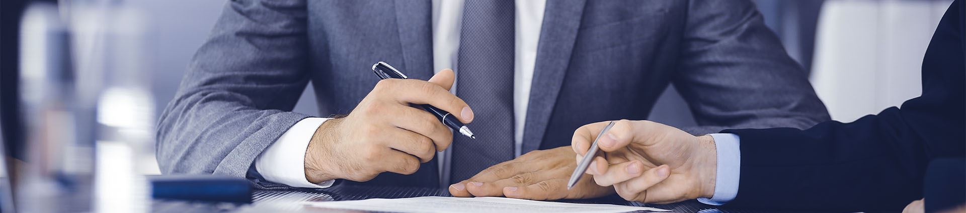 two mens' hands holding pens